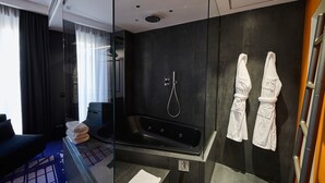 A modern bathroom with a large bathtub, a glass shower enclosure, and two white towels hanging on the wall. - MyTALE Creative Academy Hotel (Rome)