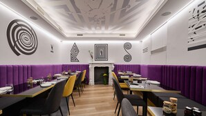 A modern dining area with purple booths, black and yellow chairs, and a central fireplace. - MyTALE Creative Academy Hotel (Rome)