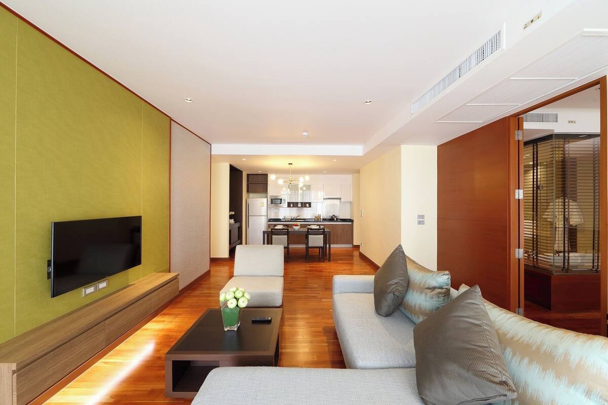 Una sala de estar moderna con un televisor de pantalla plana, una mesa de centro con un florero y un sofá.