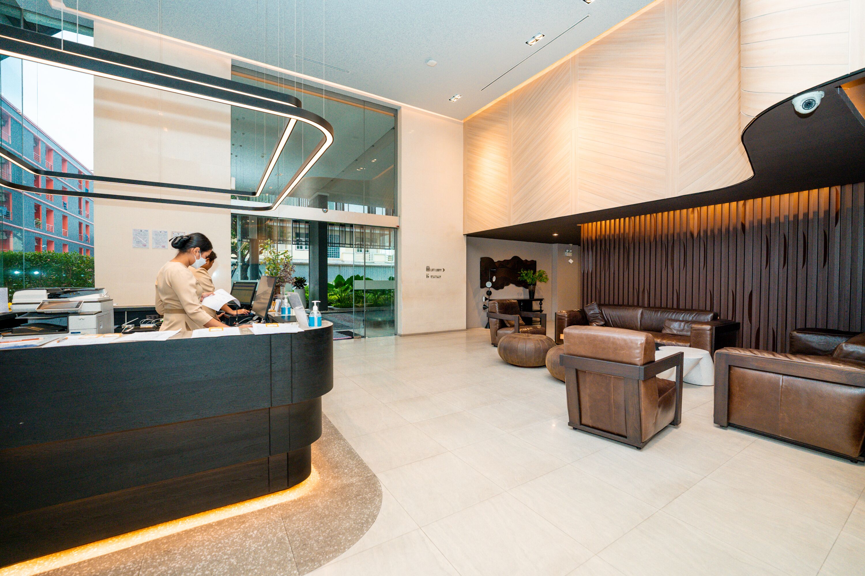 A modern reception area with a reception desk, seating area with leather sofas, and a large window overlooking the cityscape.