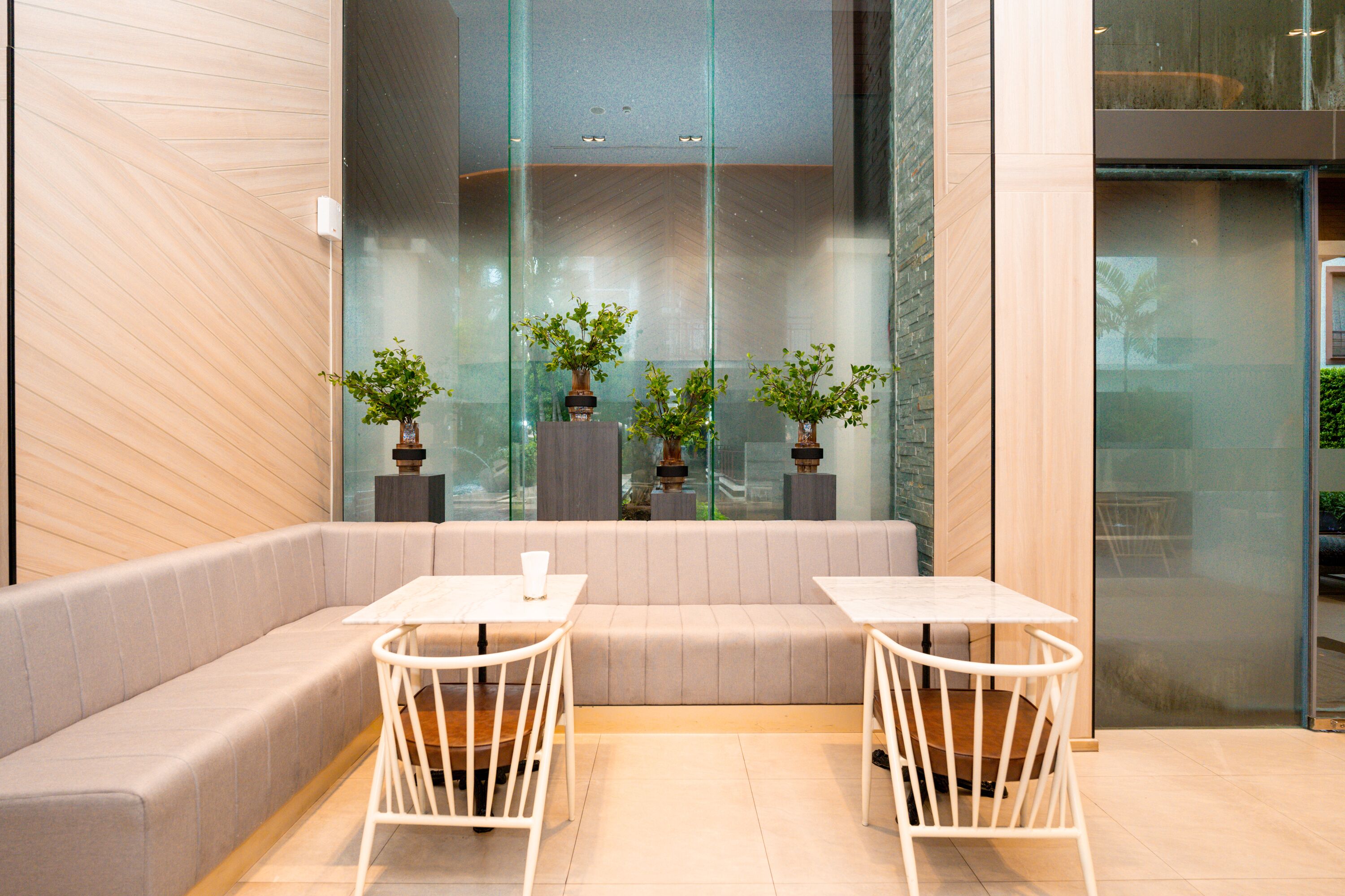 A modern indoor seating area with cushioned benches and white metal tables.