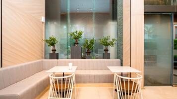 A modern indoor seating area with cushioned benches and white metal tables.