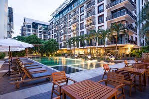 A hotel pool area with sun loungers, tables, and umbrellas. - Amanta Hotel & Residence Ratchada (Bangkok)