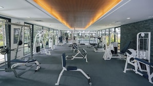 Un gimnasio moderno con diversos equipos de ejercicio, ventanas amplias y techo de madera.