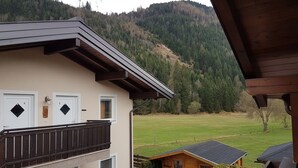 Un edificio di due piani con porte numerate, un balcone e vista su un prato verde e una collina boscosa.