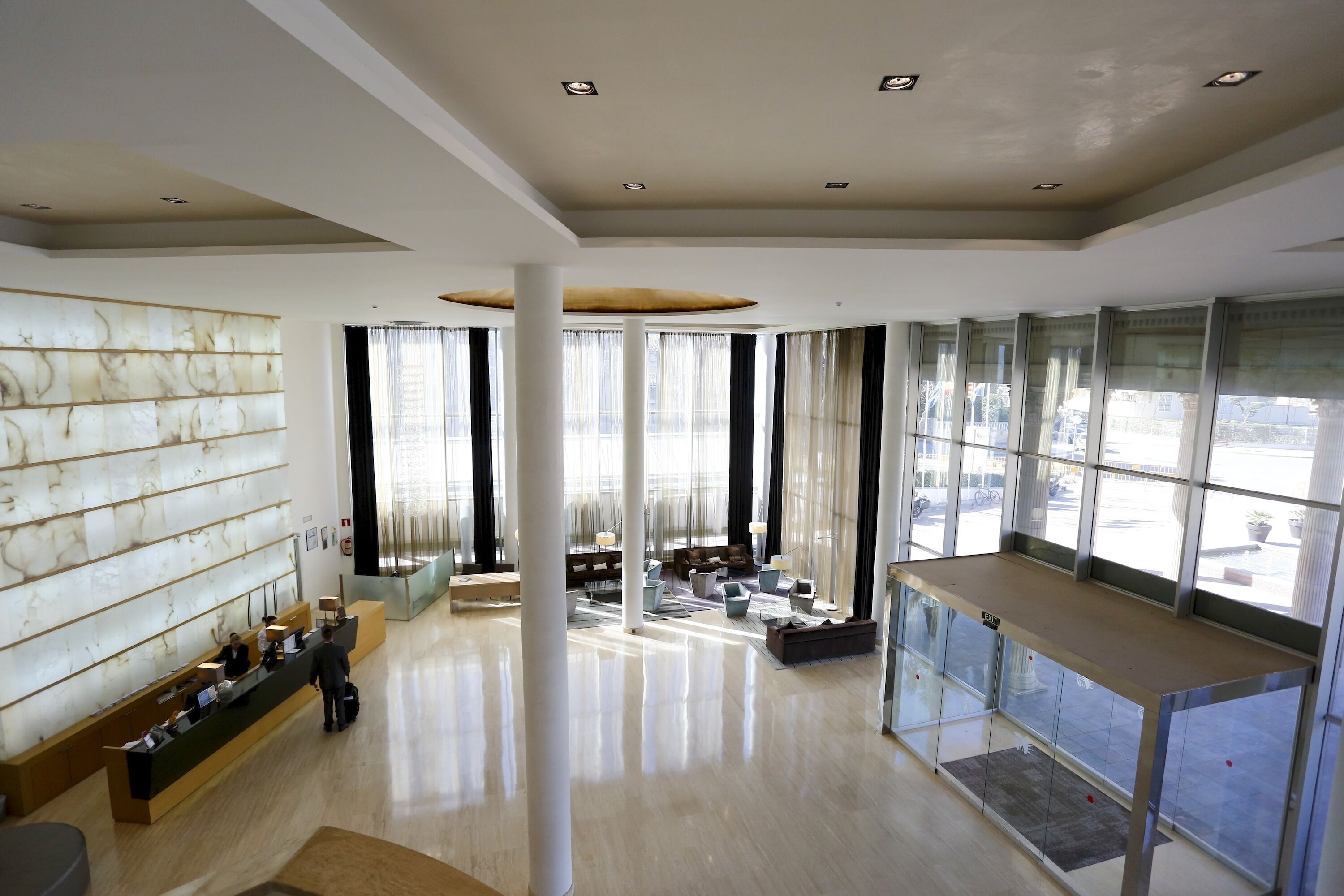 A spacious lobby with a reception desk, seating area, and large windows offering views of the outside.