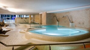 A large indoor swimming pool with multiple hot tubs, surrounded by tiled walls and a glass railing. - Gran Palas Hotel - Spa incluido (Vila-Seca)