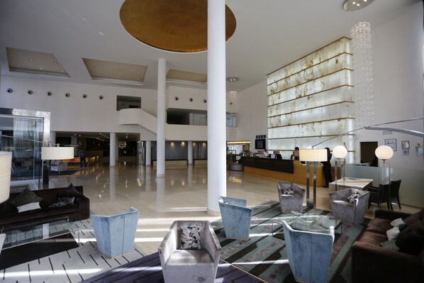 Un vestíbulo amplio con techos altos, muebles modernos y un mostrador de recepción central.