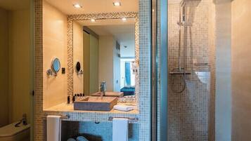 Un baño moderno con un espejo grande, dos lavamanos, una ducha y zona de ducha con mampara de vidrio.