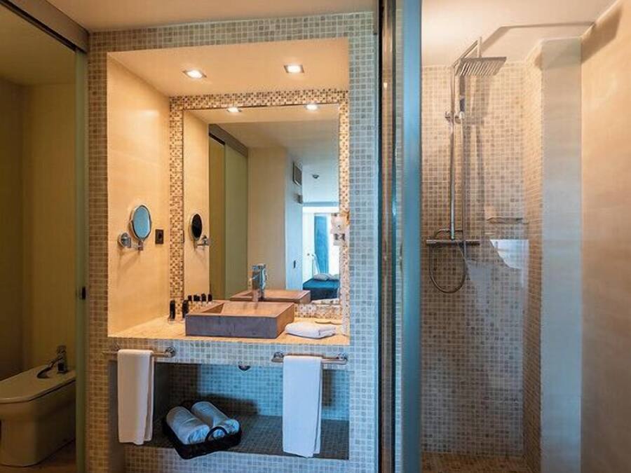 A modern bathroom with a large mirror, two sinks, a shower, and a glass-enclosed shower area.