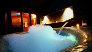 A hot tub with a water fountain feature, surrounded by a tiled floor and wooden walls. - Gran Palas Hotel - Spa incluido (Vila-Seca)