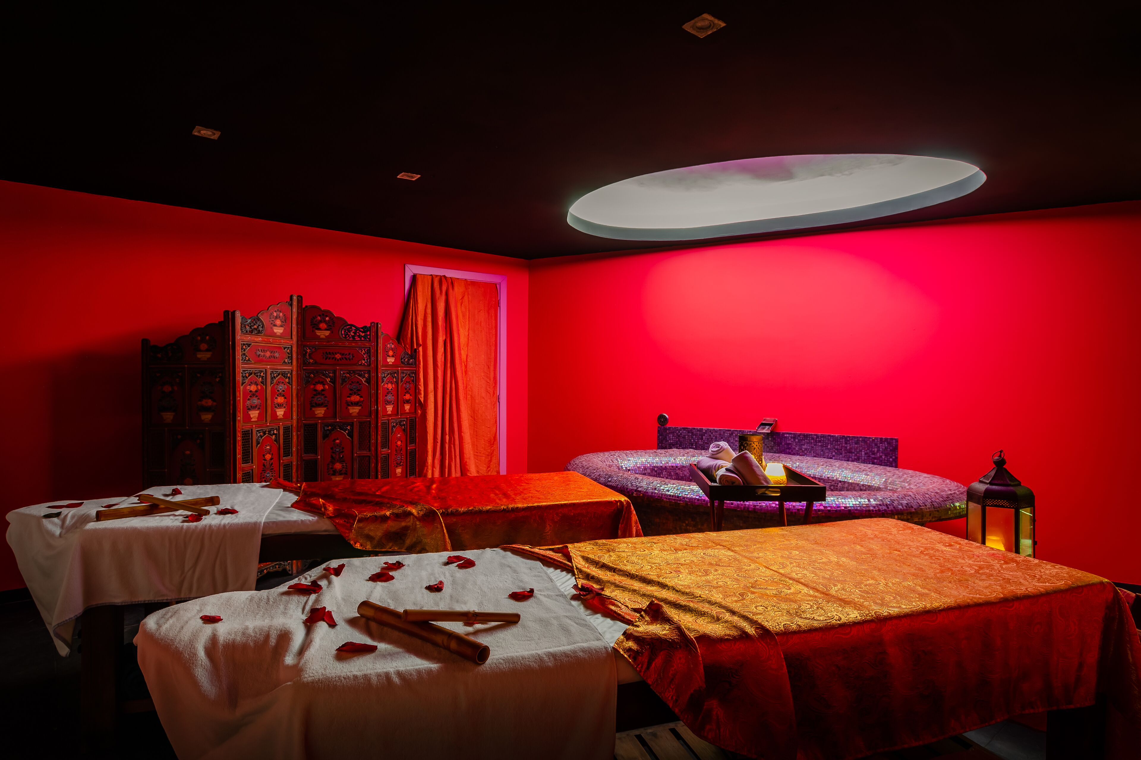 A room with two beds, a wooden cabinet, and a small table with a lamp.