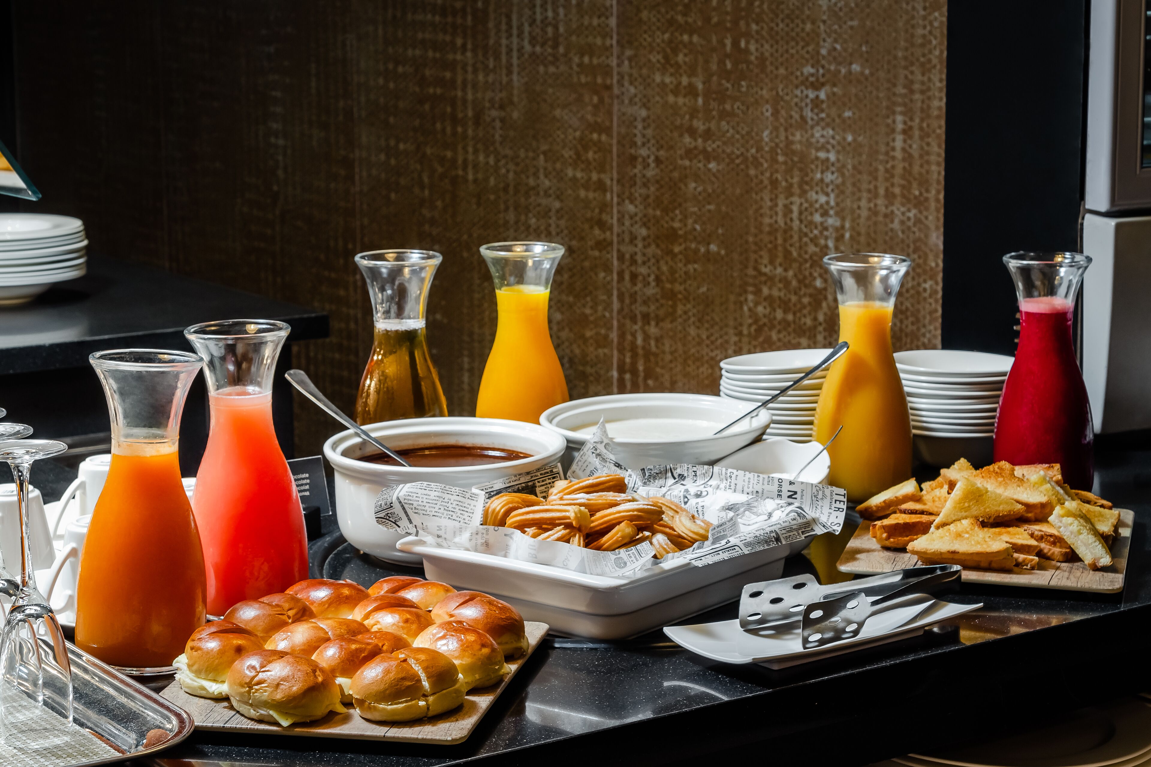 Un bufé de desayuno con diversos alimentos, bebidas y acompañamientos.