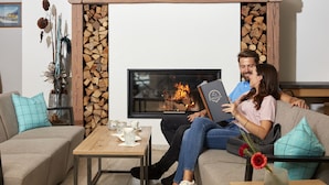 A cozy living room with a fireplace, a sofa, a coffee table, and decorative items. - Hotel Zontaja (Galtur)