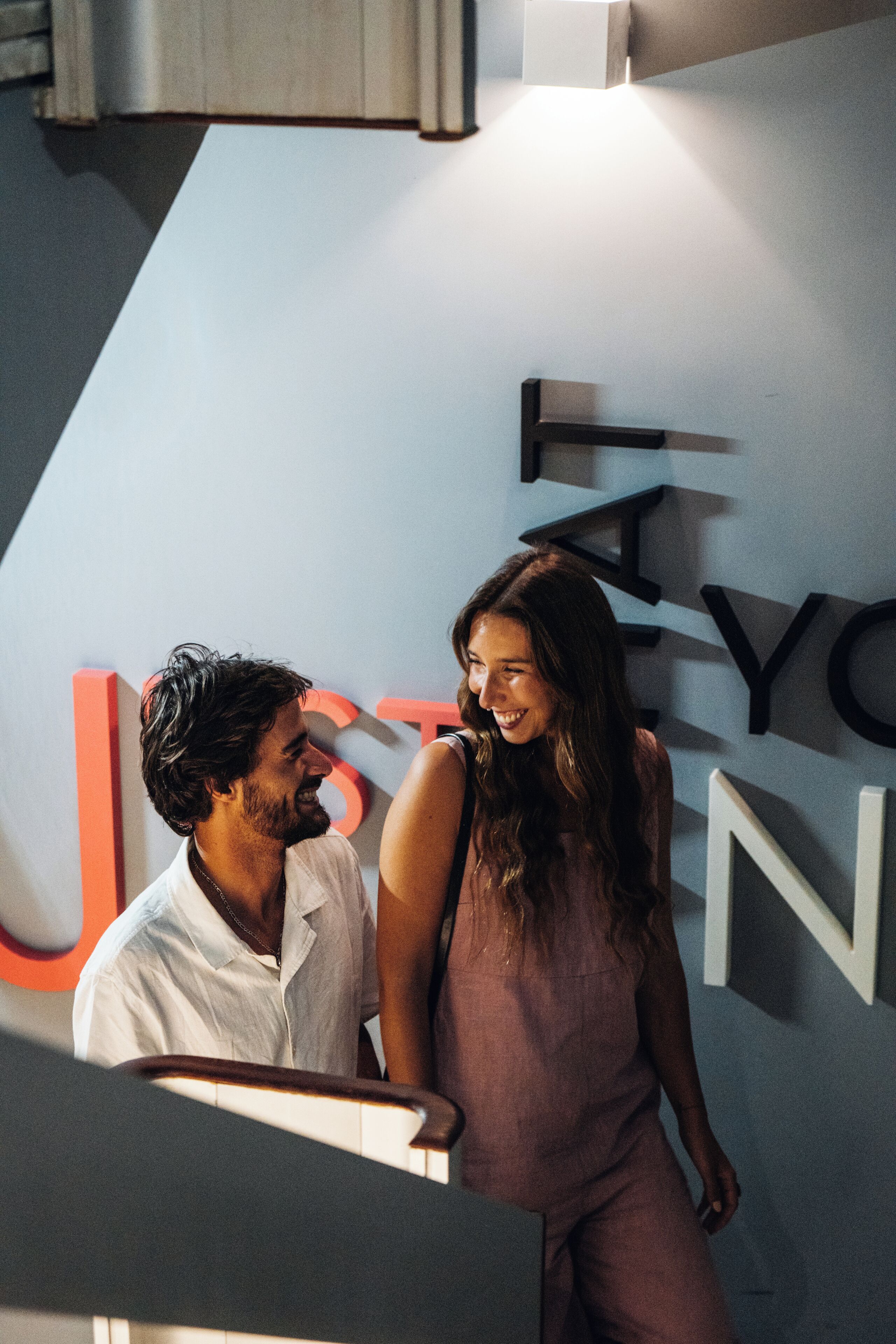 A man and a woman standing in front of a wall with large letters.