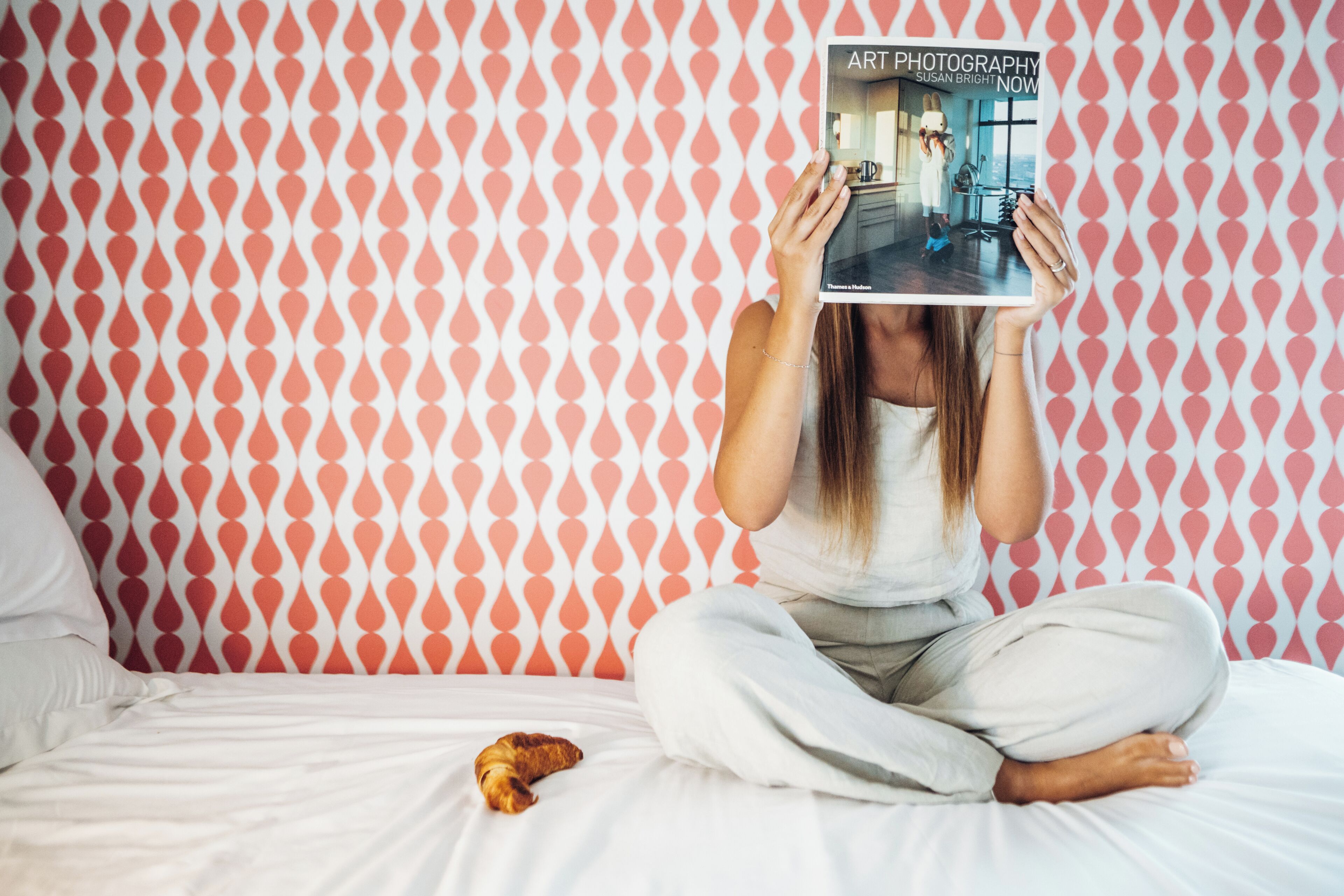 A person sitting on a bed with a book titled "Art Photography" in front of them.