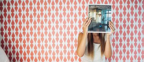 A person sitting on a bed with a book titled "Art Photography" in front of them.