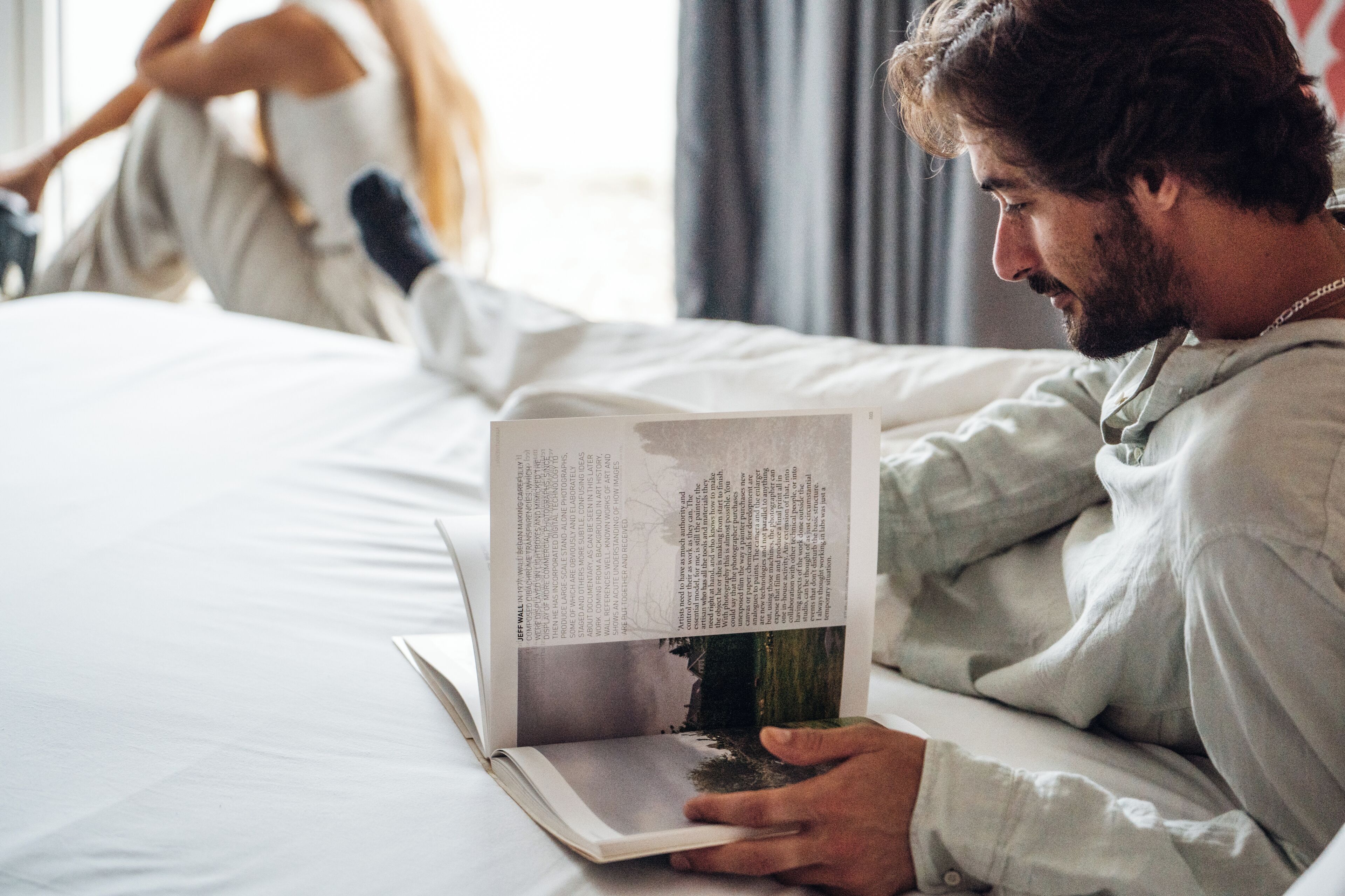 A person lying on a bed reading a book.