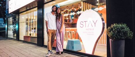A hotel entrance with a large illuminated sign reading "STAY HOTELS PORTO CENTRO TRADADE".