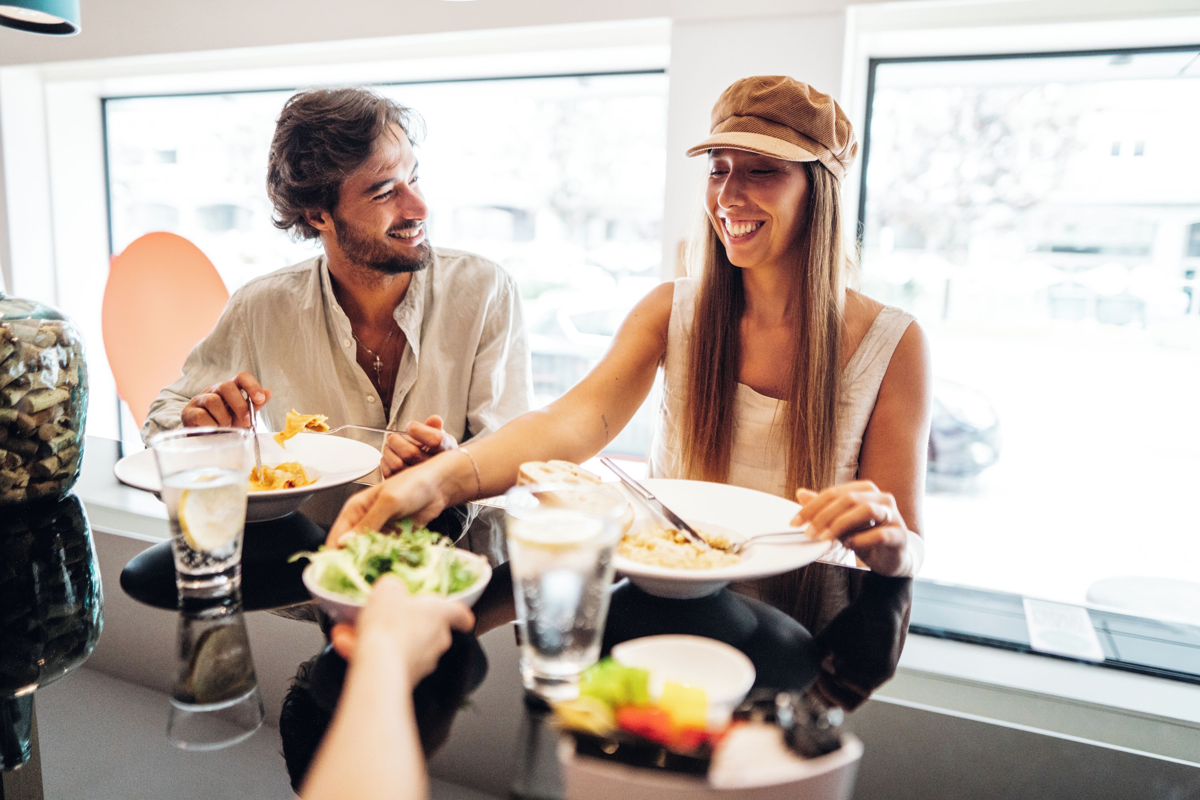 A dining table with plates of food, glasses, and a salad bowl.