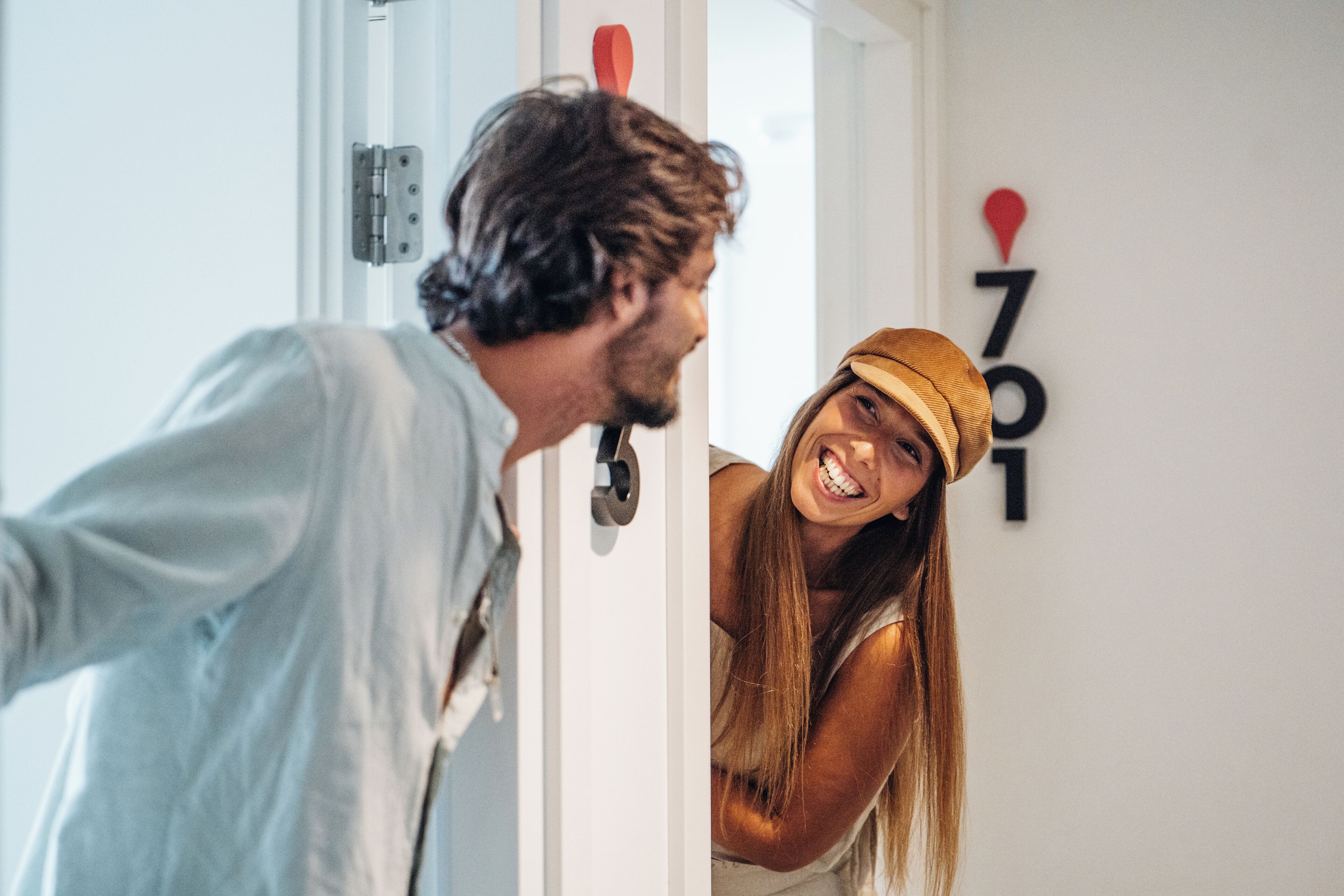 A person opening a door to a room with a number sign on the wall.