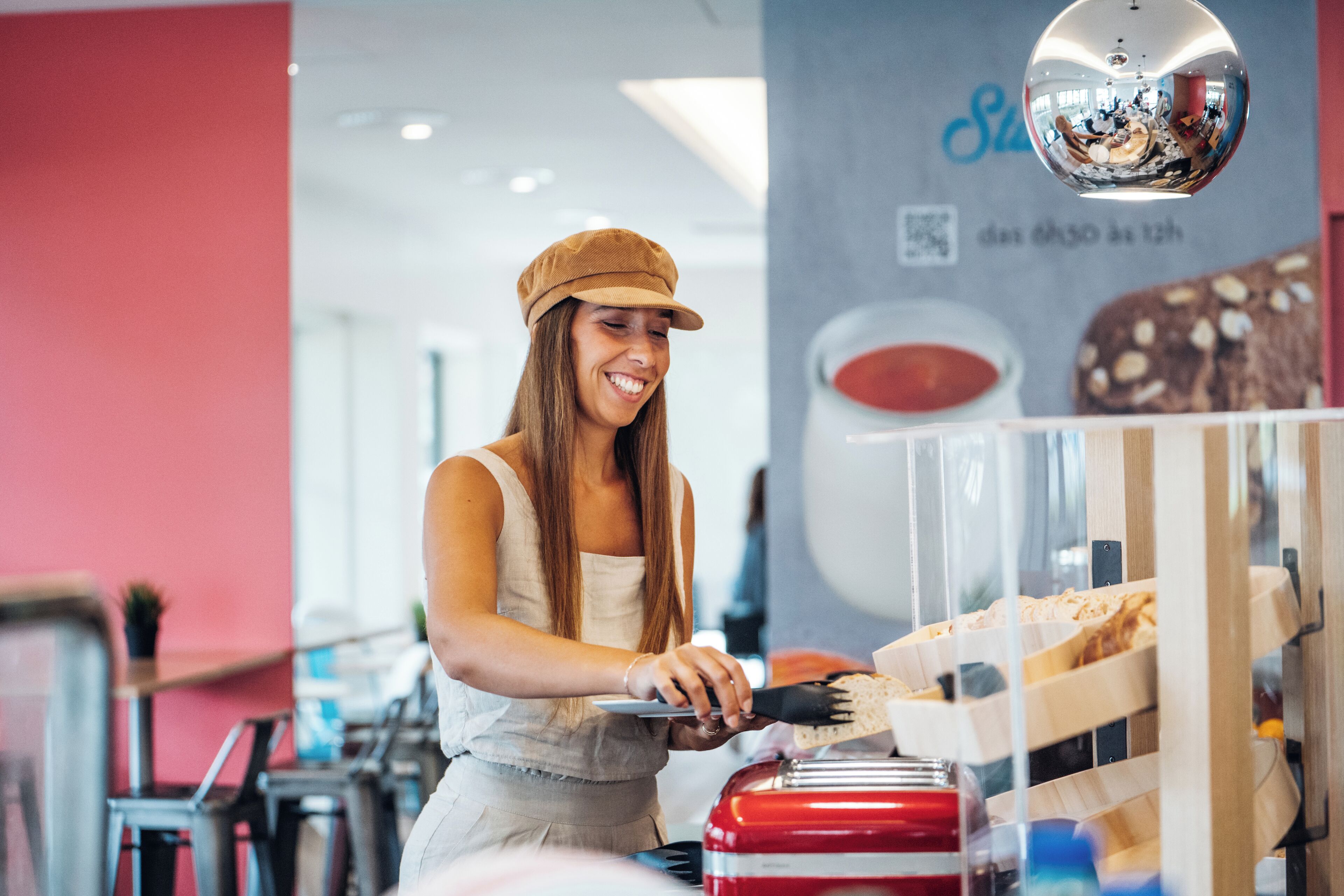 A person serving food in a modern restaurant with a red and white color scheme.