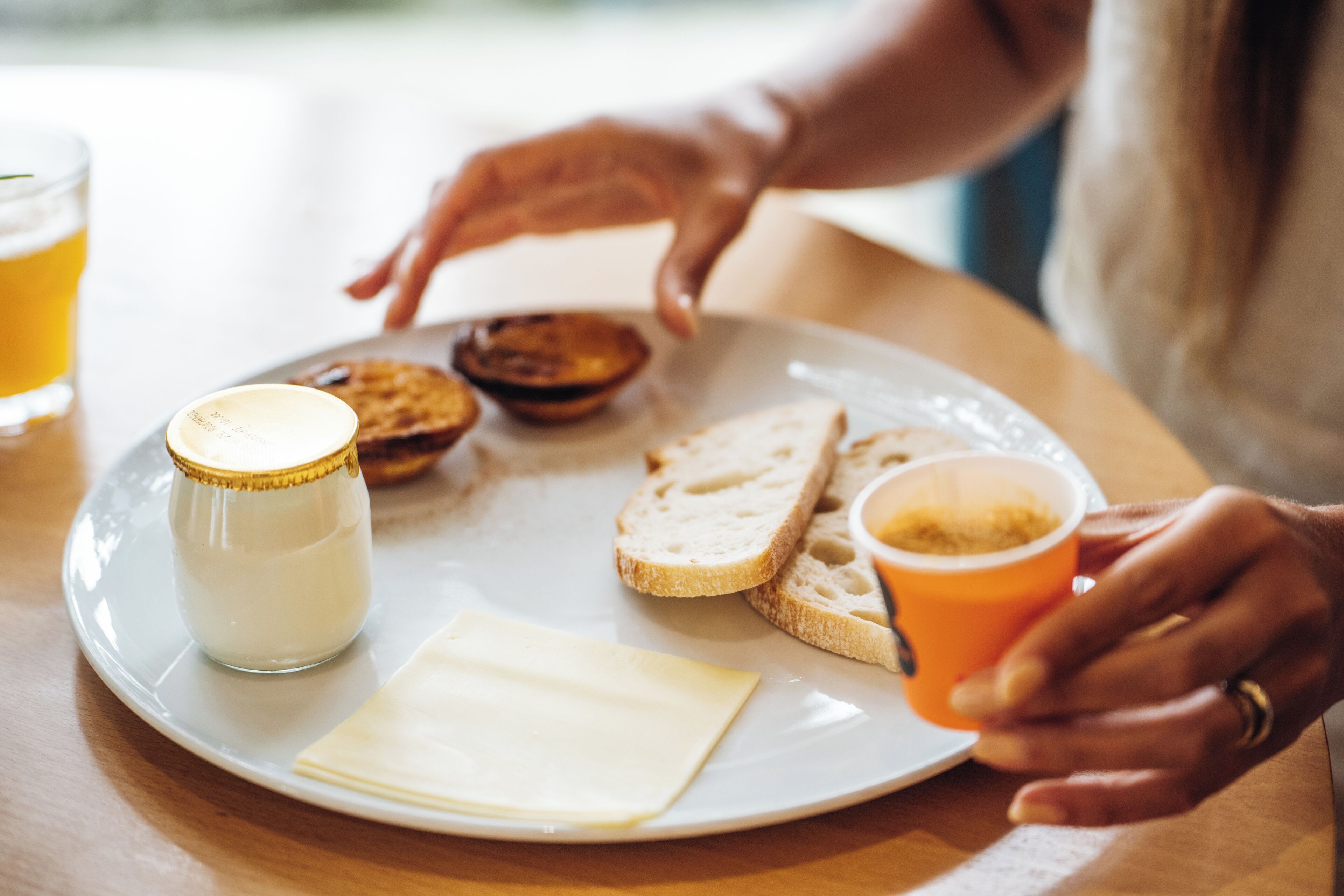 A plate with cheese, bread, and a drink on a table.