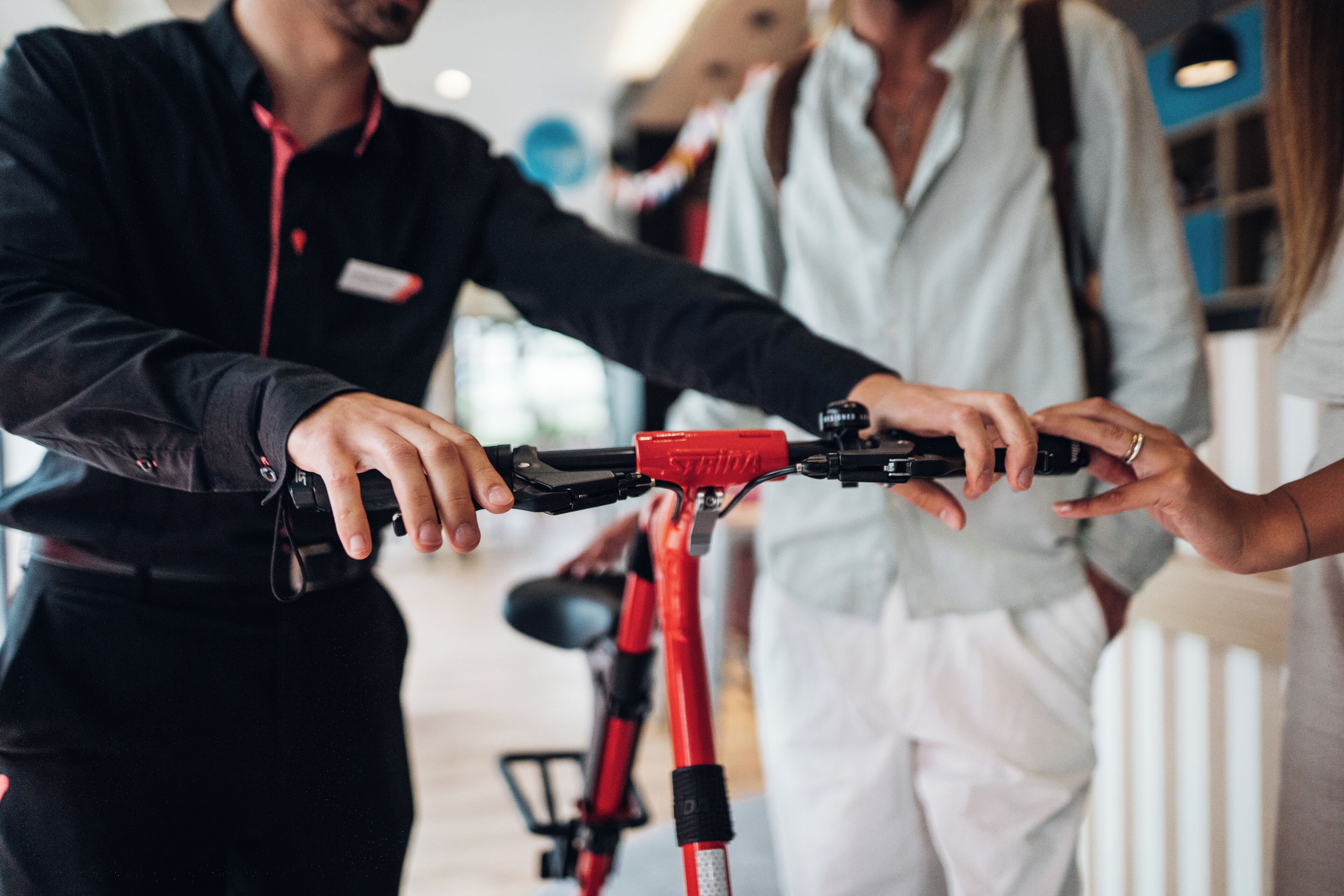 A person holding a red bicycle with a black handlebar.