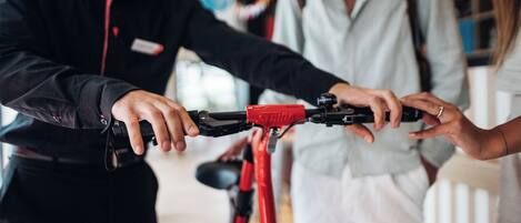 A person holding a red bicycle with a black handlebar.