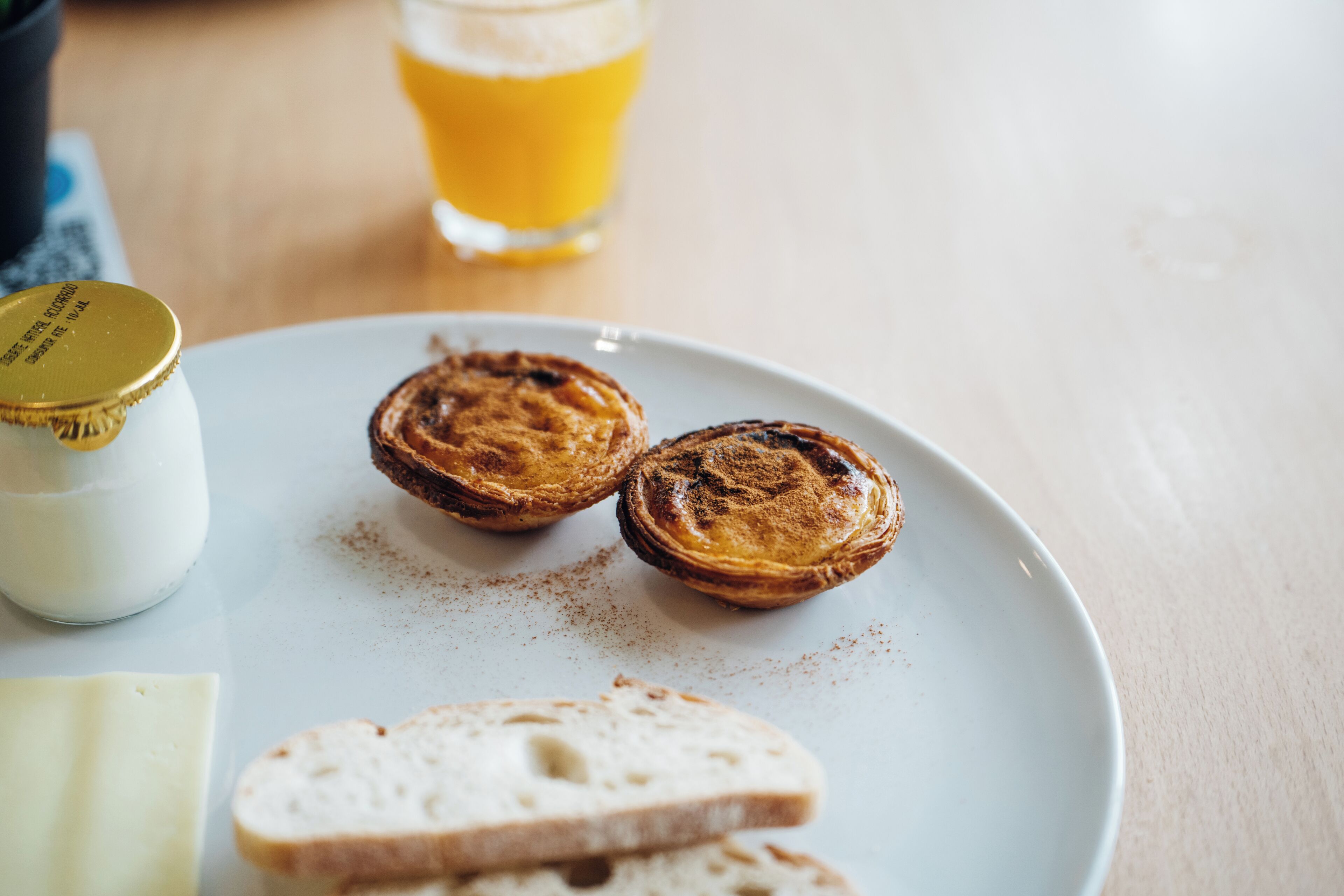 A plate with three pastries and a glass of orange juice on a table.