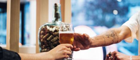 A person holding a glass of beer at a bar with a bottle in the background.
