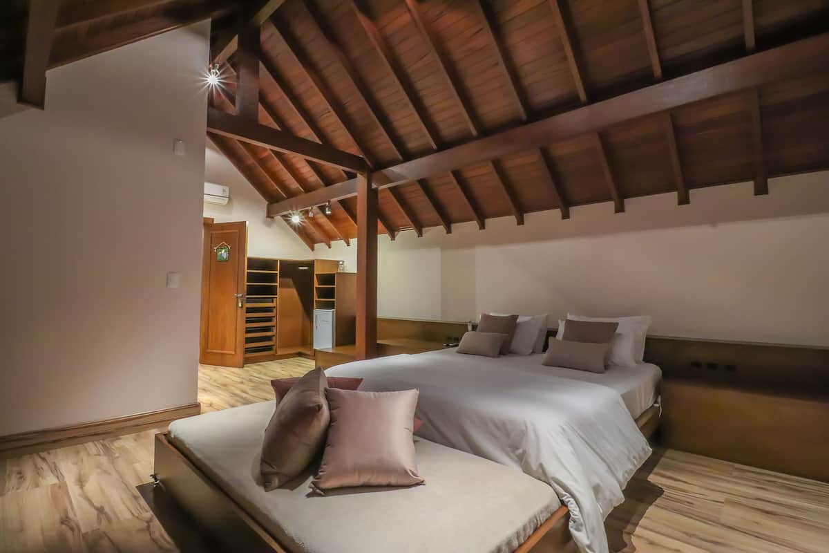 Une chambre avec un plafond en bois, un lit recouvert de plusieurs oreillers et un plancher en bois.