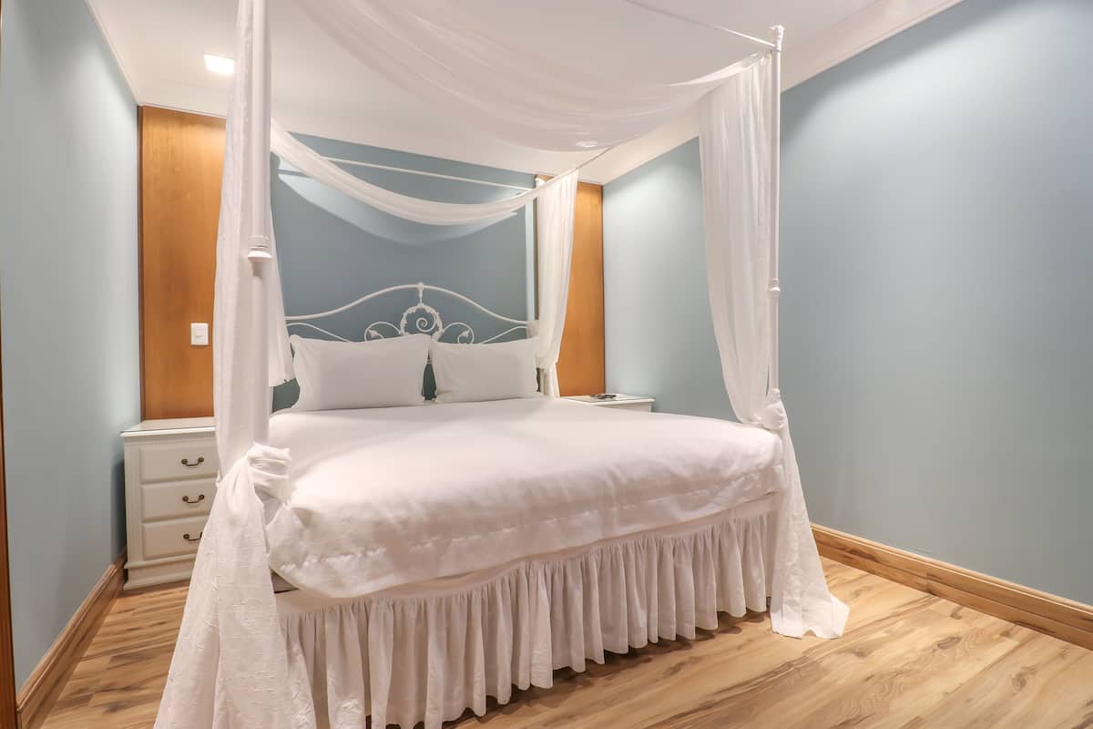 Une chambre à coucher bien aménagée, avec un lit à baldaquin, une table de chevet et une petite table de nuit.
