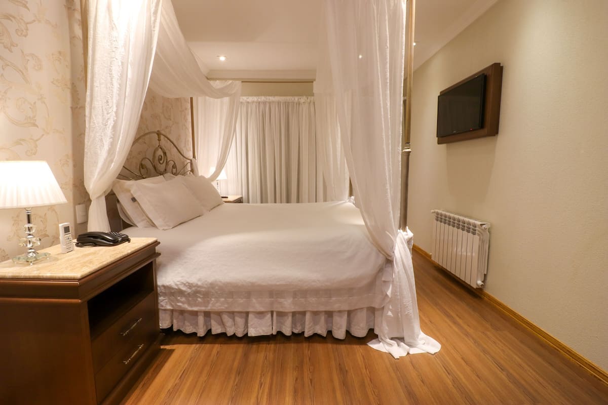 Une chambre à coucher bien rangée, avec un lit, une table de chevet, une lampe et un téléviseur fixé au mur.