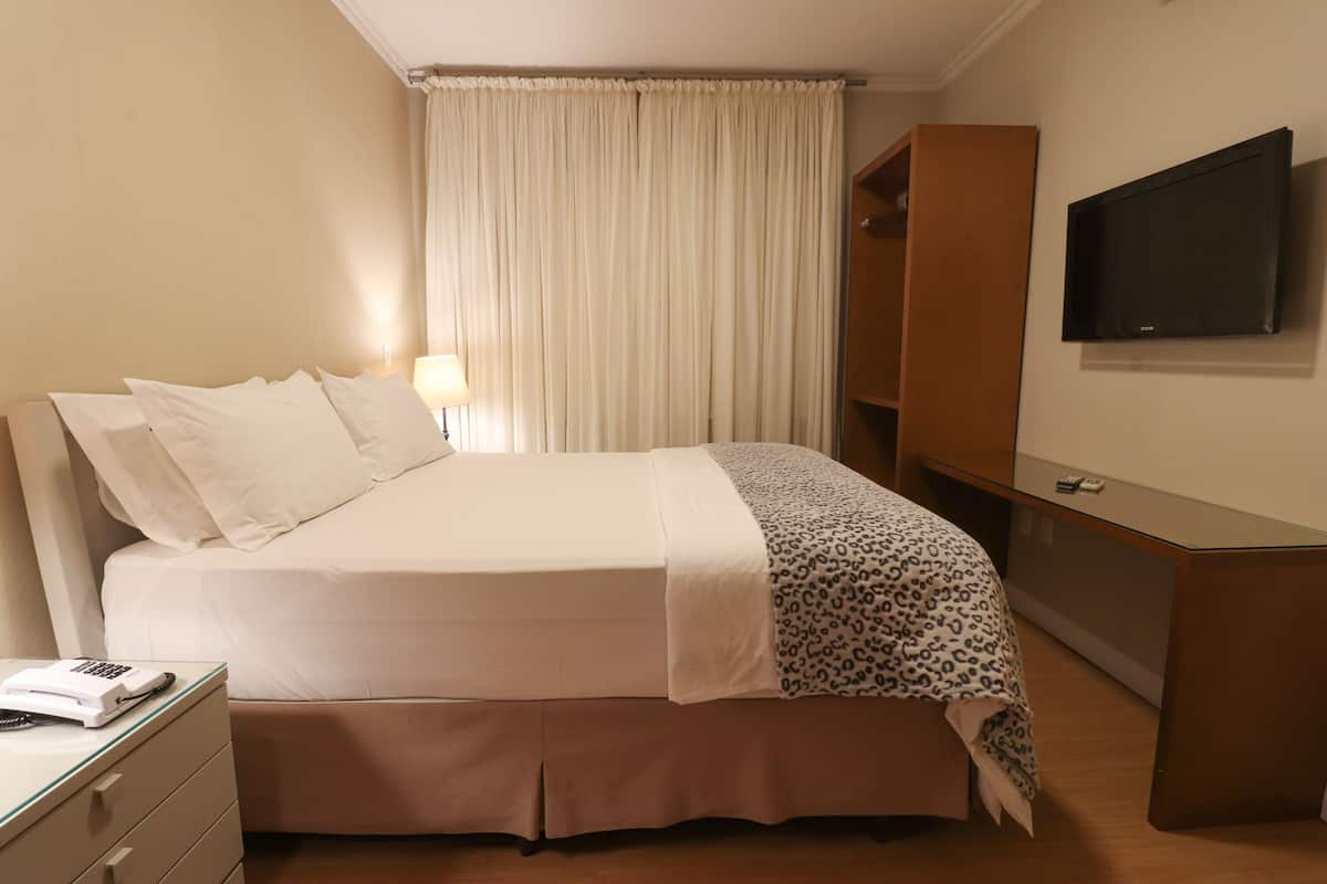 Une chambre d’hôtel équipée d’un lit, d’un bureau, d’une chaise, d’une télévision et d’une armoire.