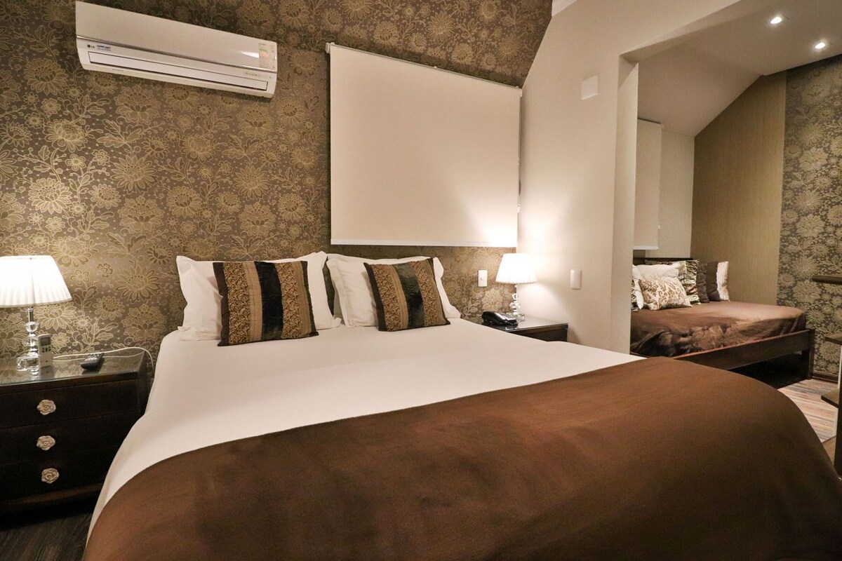 Ein Schlafzimmer mit einem großen Bett, einem Nachttisch mit Lampe, Telefon und einer Klimaanlage an der Wand.