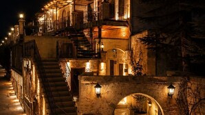 A stone building with a staircase, a sign reading 'Sakir Cave House Hotel,' and outdoor lighting. - Saklı Cave House (Avanos)
