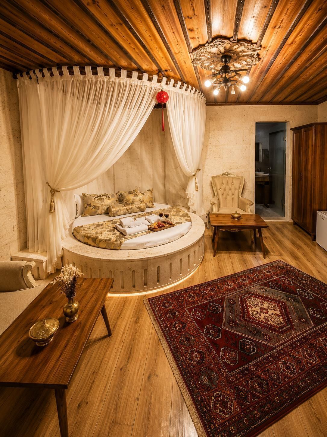 Ein gemütliches Schlafzimmer mit einem runden Bett, einer Holzbalkendecke und einem roten Teppich mit Muster.