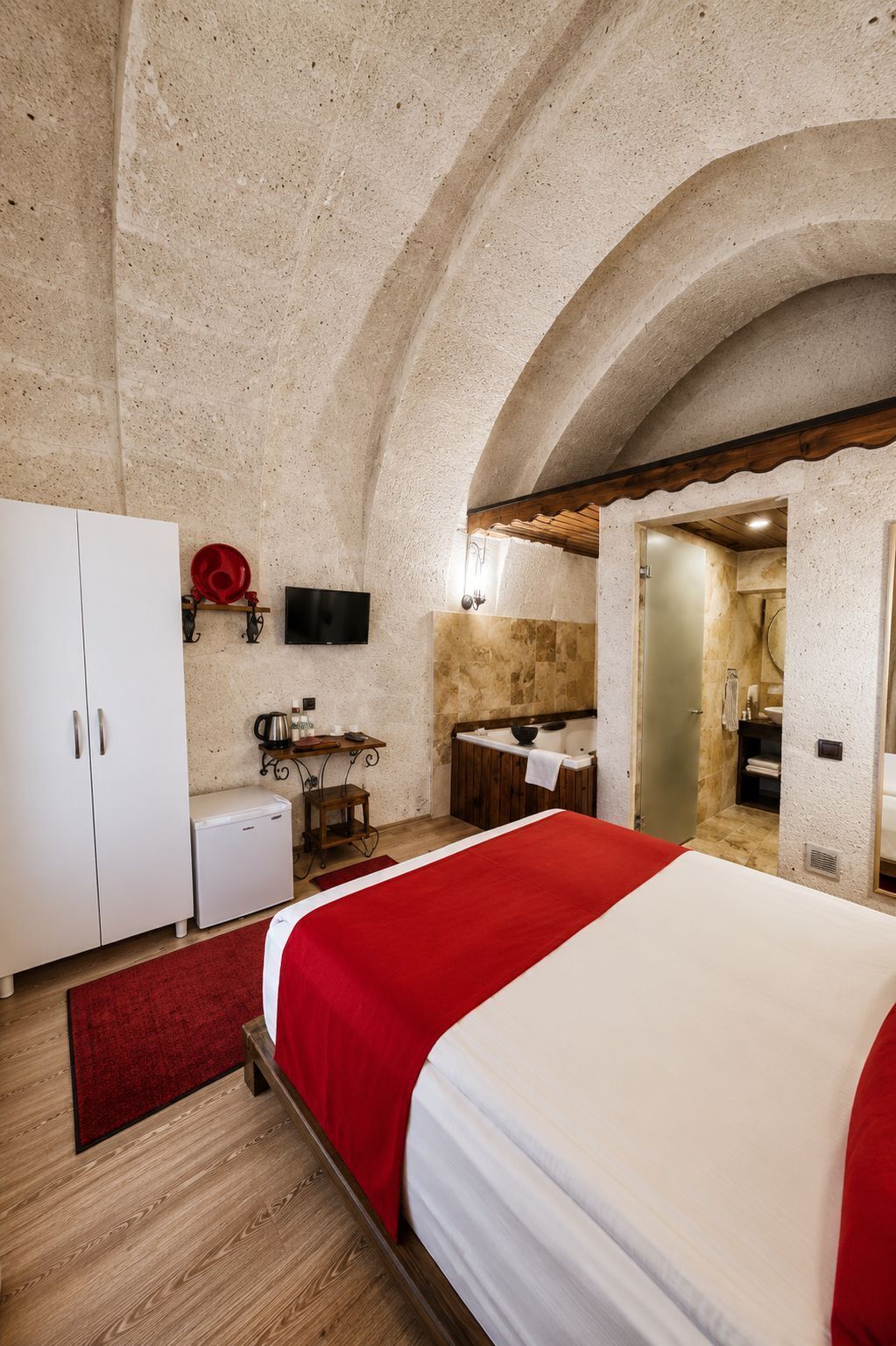 A bedroom with a bed, a small kitchenette, and a bathroom.