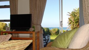Ein Wohnzimmer mit Fernseher, Rattanmöbeln und Meerblick.