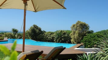 Relax by the serene pool surrounded by lush greenery and ocean views.