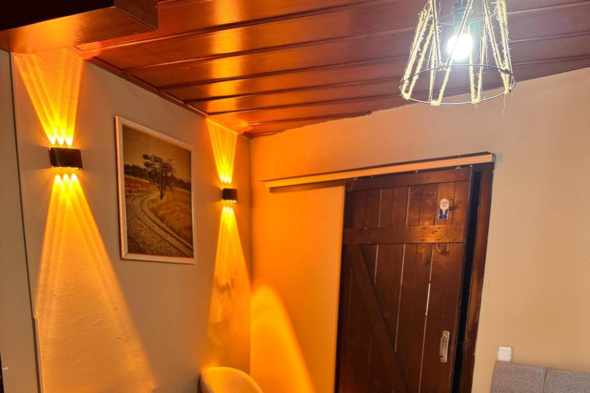 A hotel room with a bed, two chairs, a small table, and a wooden door.