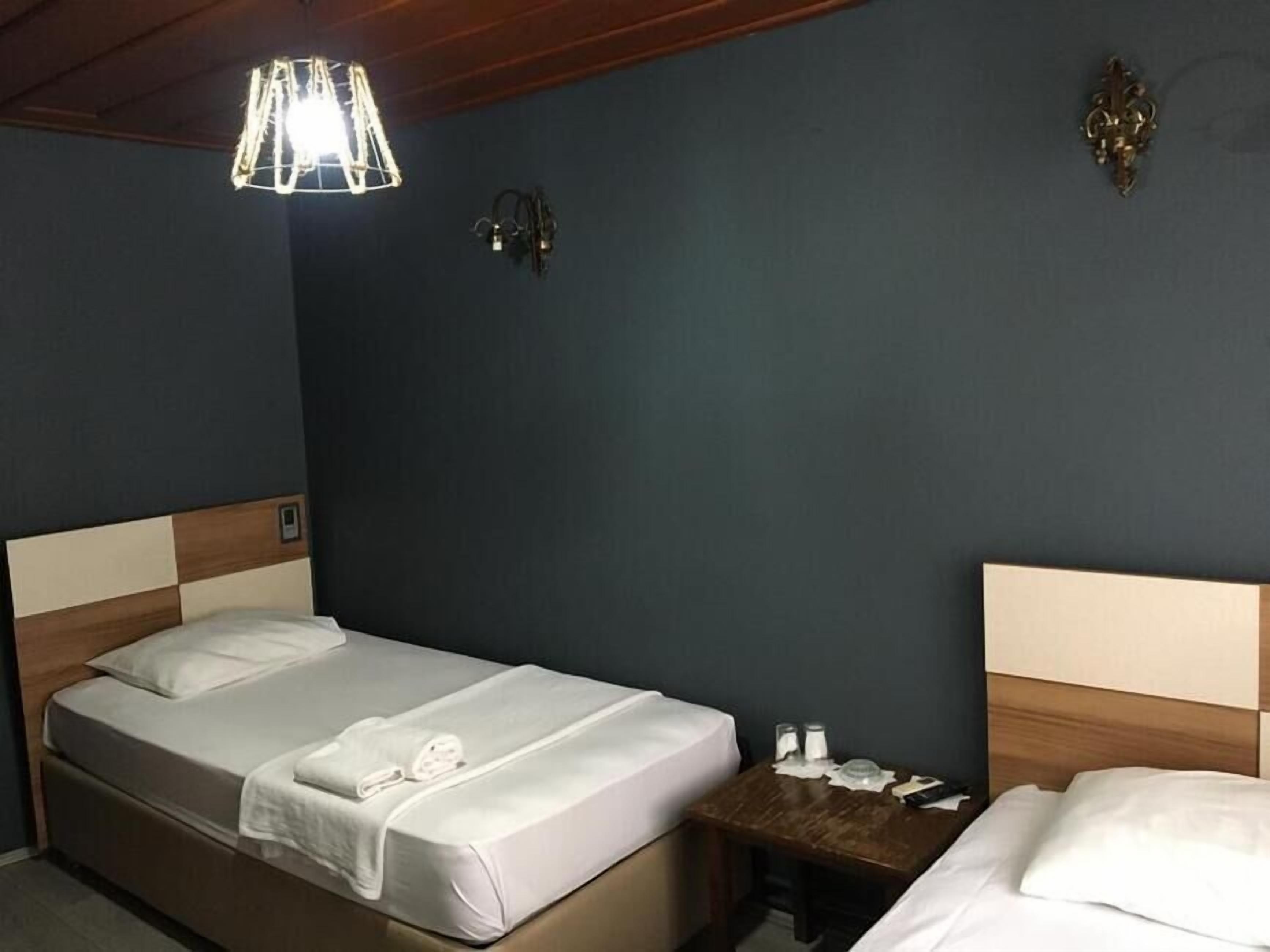 Una habitación de hotel con cama, mesita de noche y lámpara colgante.