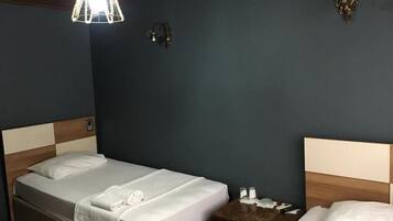 Una habitación de hotel con cama, mesita de noche y lámpara colgante.