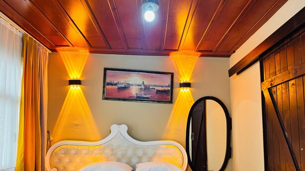 A hotel room with a bed, a headboard, a bedside table, a mirror, and a painting on the wall. - Onuncu Koy Hotel - Adults Only (Bursa)