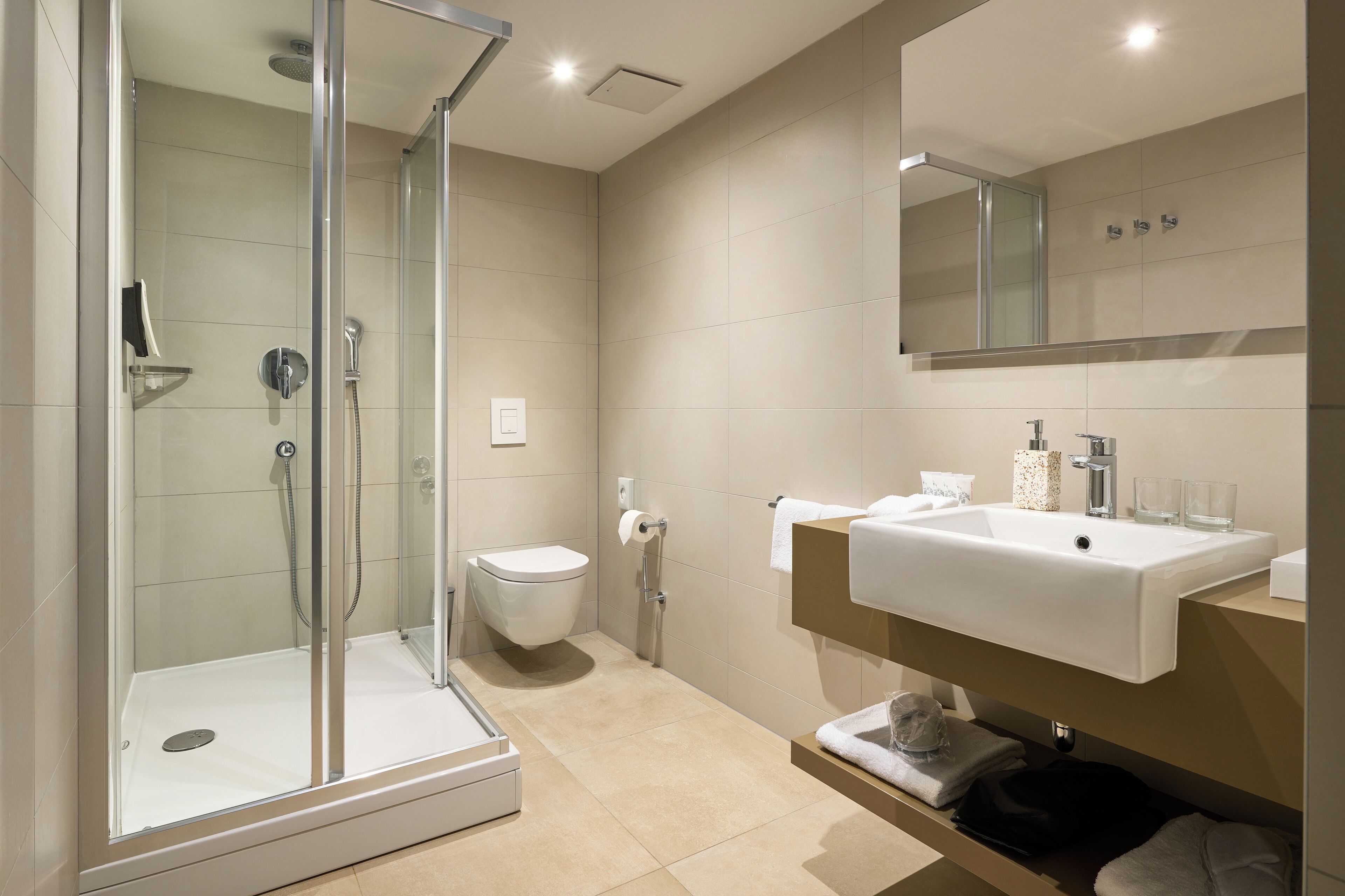 A modern bathroom with a glass-enclosed shower, a white sink, and a toilet.