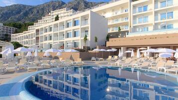 Ein Hotel mit Schwimmbad, Liegestühlen und Sonnenschirmen.