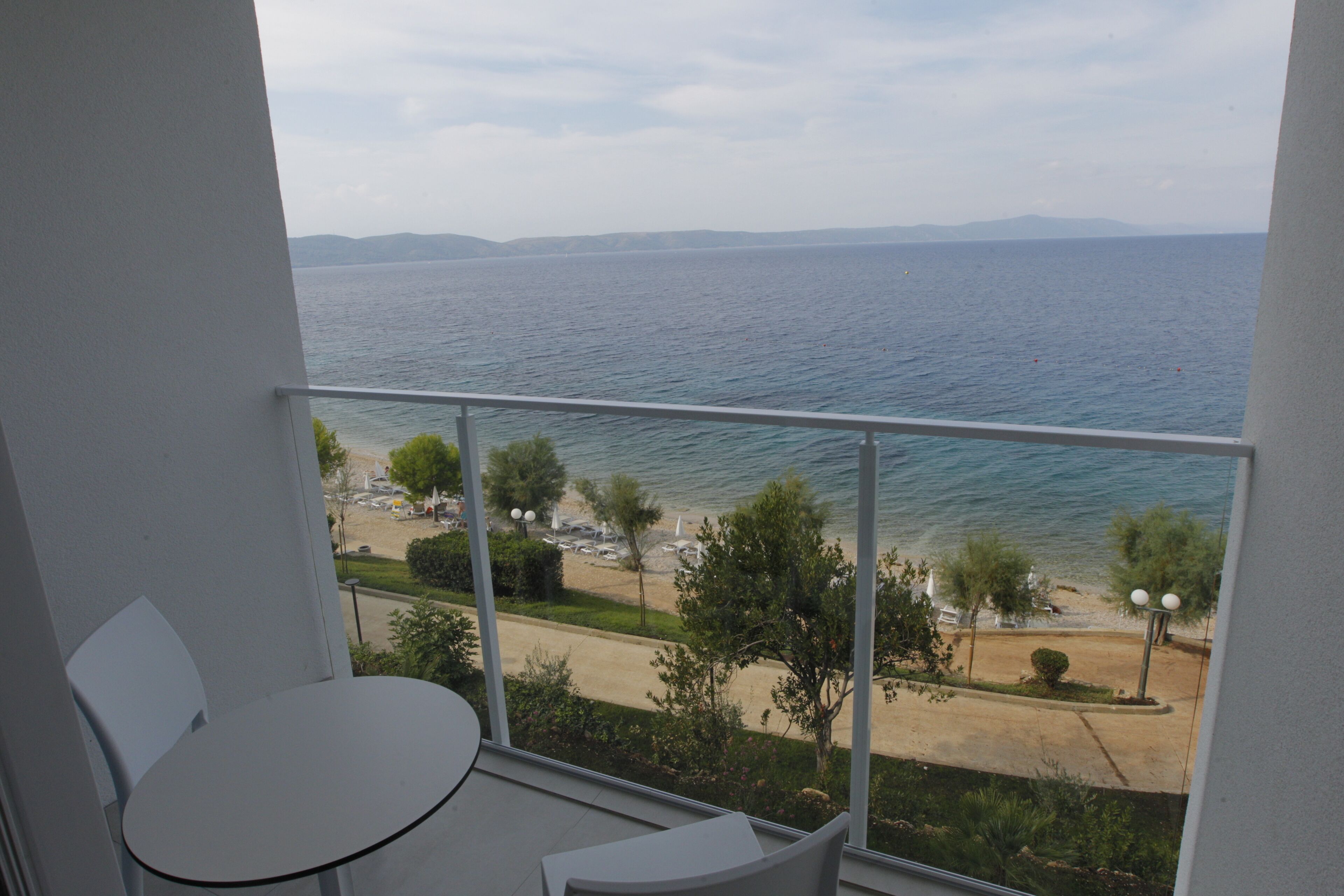 Un balcón con vistas al mar, una mesa y sillas.