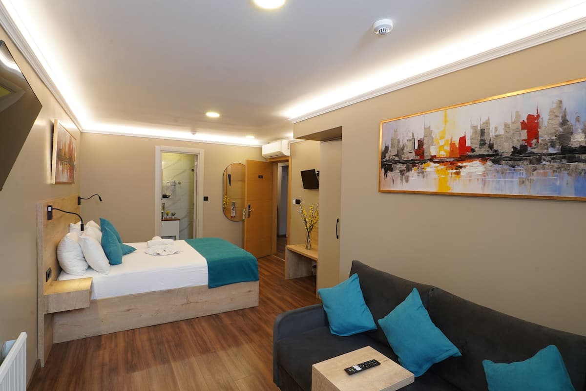 Ein Hotelzimmer mit einem Bett, einer Couch, einem Fernseher und einem Gemälde.