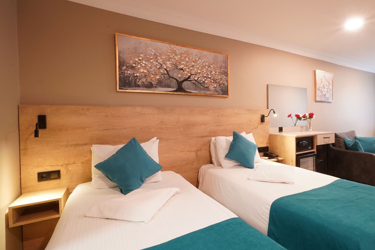 Ein Hotelzimmer mit zwei Betten, einem Schreibtisch, einem Stuhl und einem Bild an der Wand.